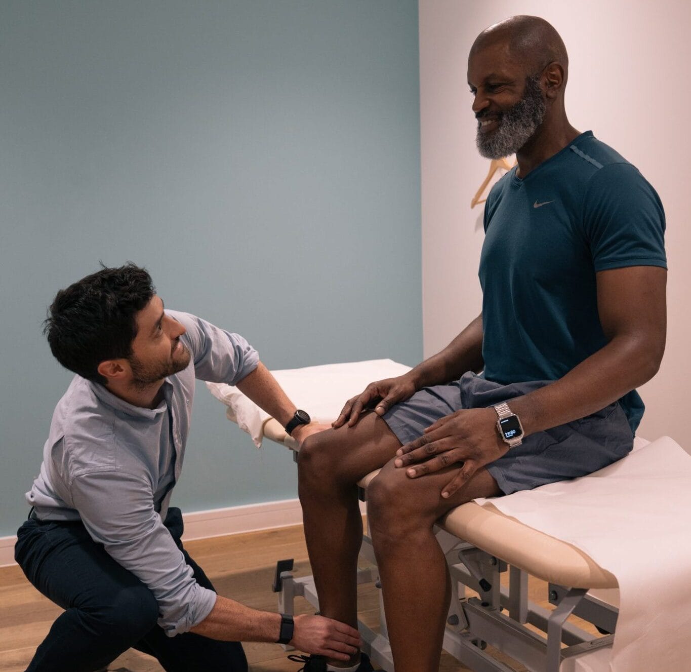 a clinician holding a patient's ankle who is sat on the bed